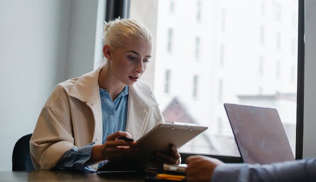 person with blond hair reviewing a contract on a clipboard